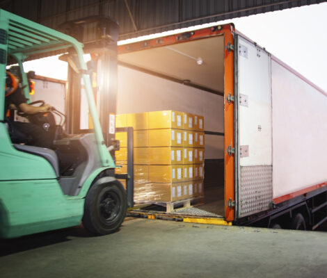 Forklift Driver Loading Package Boxes into Cargo Container. Cargo Trailer Truck Parked Loading at Dock Warehouse. Shipment Delivery Service. Shipping Warehouse Logistics. Freight Truck Transportation.