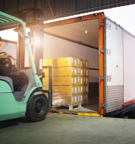 Forklift Driver Loading Package Boxes into Cargo Container. Cargo Trailer Truck Parked Loading at Dock Warehouse. Shipment Delivery Service. Shipping Warehouse Logistics. Freight Truck Transportation.